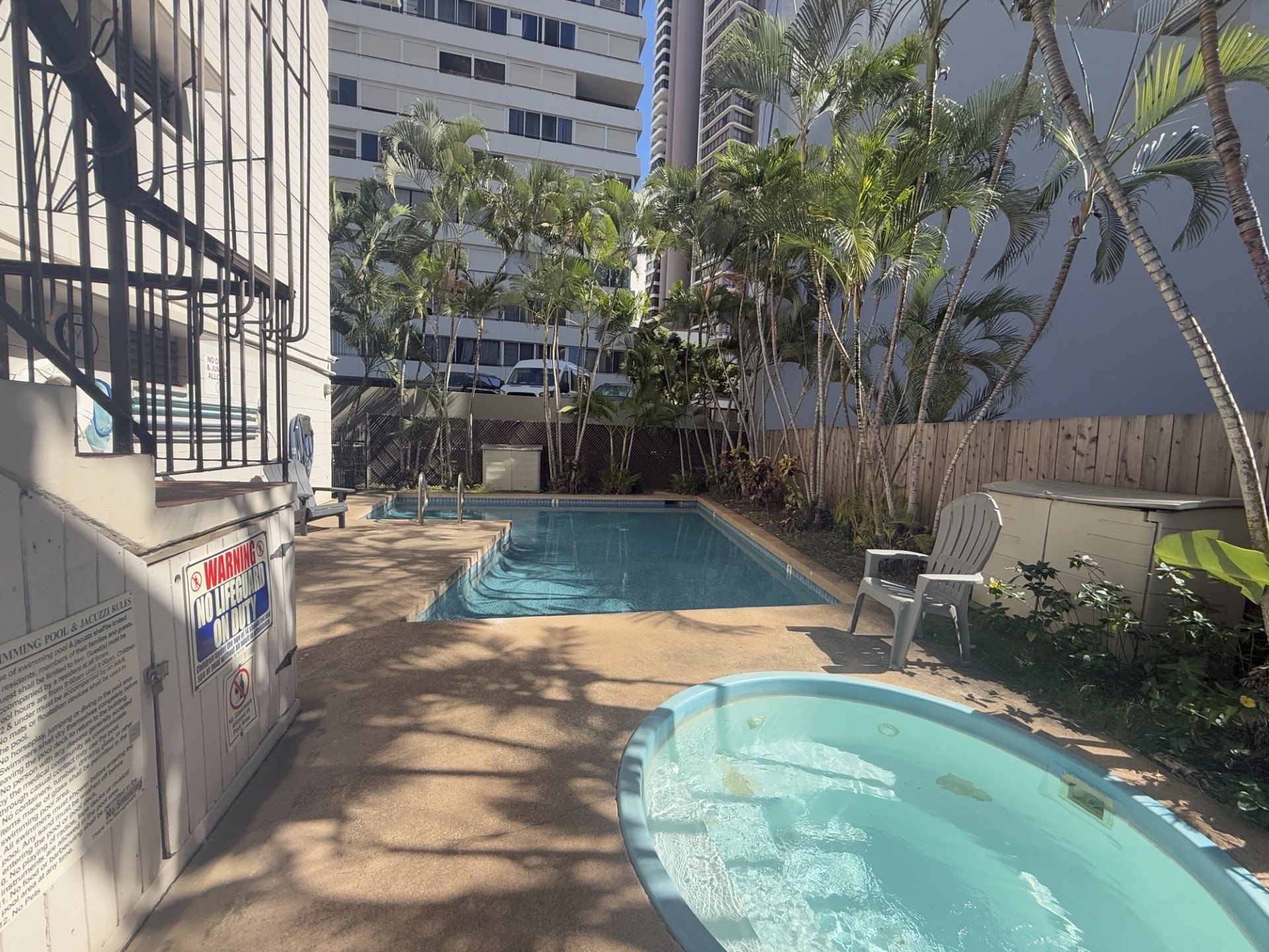 A pool with a chair and a building in the background.